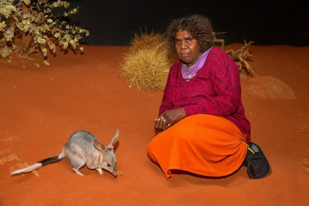 Sally Napurula Butler sitting next to a bilby at the Alice Springs Desert Park, 2016. 