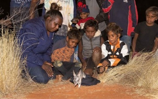 Christine Ellis, Australian Wildlife Conservancy Land Management Officer, with students from Nyirripi School release a Bilby into Newhaven Wildlife Sanctuary.