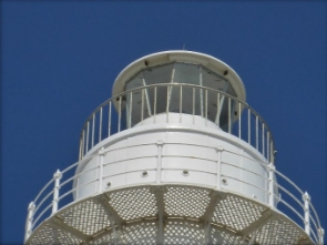 Photograph showing two tiers of white balconies encircling a glazed lighthouse lantern room.  