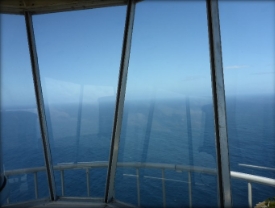 Photograph showing glazed panes of lighthouse lantern room. Ocean and sea can be seen outside. 