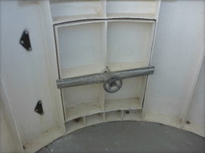 Photograph showing small, closed door with small handwheel fitted to inside of door. 