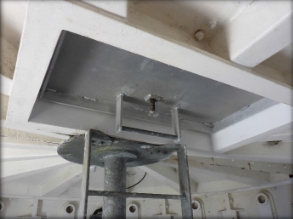 Photograph showing underside of lantern room with a small closed, aluminium hatch. A steel ladder is fixed below the hatch. 