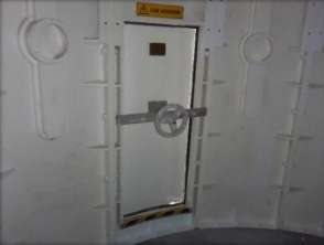 Photograph showing large, closed lantern room door with large handwheel fitted to inside of door. 