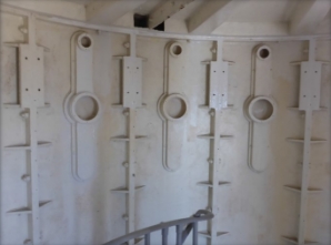 Photograph showing inside a lighthouse room with cast iron panels bolted together. Round air inlets are fitted in the panels.  