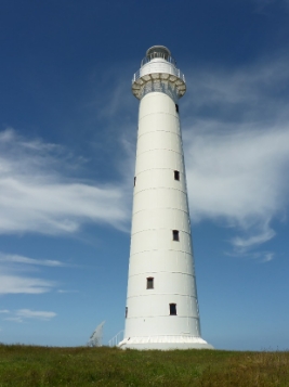 Photograph showing tall, white lighthouse tower against a blue sky. 