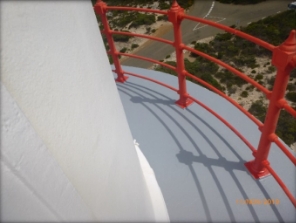 Photograph showing curved balcony floor of lighthouse tower. Curved red handrails fitted to outer edge of floor.