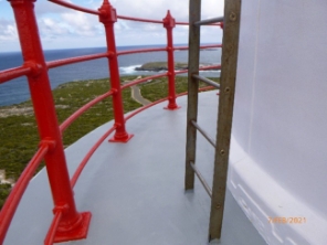 Photograph showing balcony floor with curved red handrails fitted to outer edge. A steel ladder is fitted to balcony floor.