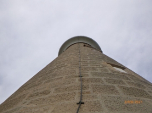 Photograph showing view of stone lighthouse from the foot of the tower. A lightning conductor runs up the length of the tower.