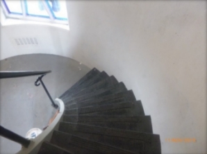 Photograph showing curved staircase leading to landing below.