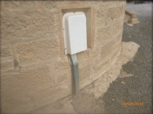 Photograph showing vent cover fitted to external stone wall of tower.