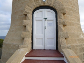 Photograph showing arched timber double doors at base of stone lighthouse tower.