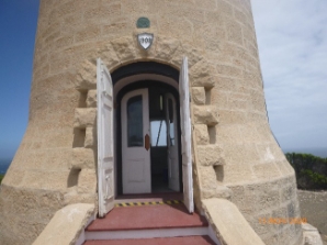 Photograph showing base of stone lighthouse tower with outer and inner tower doors standing ajar. 