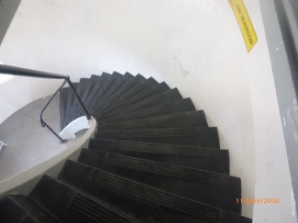 Photograph showing curved staircase leading down to circular floor below. 