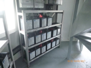 Photograph showing battery racks standing against wall of circular room.