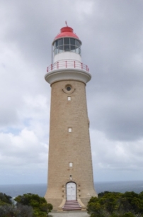 Photograph showing stone lighthouse tower with white lantern house and red dome.