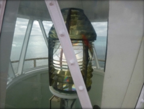 Photograph showing prismatic lens sitting on pedestal inside lantern house. 