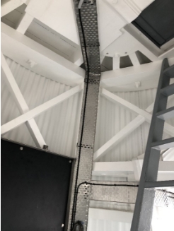 Photograph showing cable trays fitted to internal walls of lighthouse tower. The walls are timber framed and wrapped externally in corrugation.