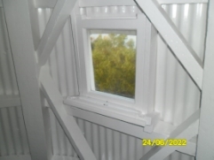 Photograph showing small rectangular window set into corrugated lighthouse wall. 