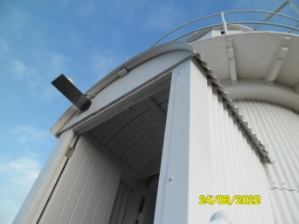 Photograph showing small, arched corrugated porch protruding from lighthouse tower. 