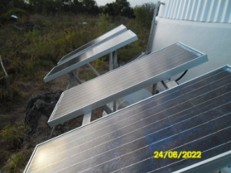 Photograph showing a row of solar panels fixed to racks at the base of lighthouse tower. 