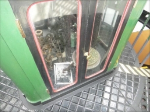 Photograph showing base of lens pedestal in the centre of the lantern room floor. Clear glass reveals an assortment of items and equipment inside pedestal.  