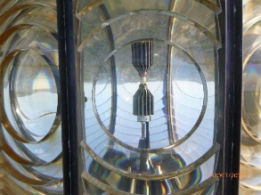 Photograph showing light emitting diode light source sitting inside large prismatic lens. 