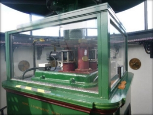 Photograph showing glass box fitted to top of pedestal. Inside the mechanism for the rotating lens can be seen. 