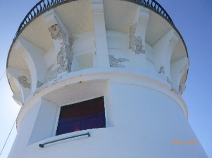 Photograph showing underside of lighthouse balcony. A large rectangular window is set into the walls below the balcony stone brackets. 