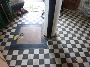 Photograph showing circular checker floor with weight tube fitted to centre of the floor, and a rectangular hatch door. 