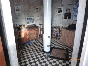 Photograph showing circular ground floor of lighthouse with a variety of cabinets and photographs on the wall.