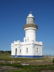 Photograph showing white lighthouse tower with attached pavilion rooms.