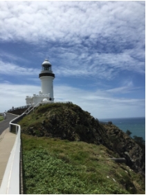 Photograph showing white lighthouse tower with attached pavilion rooms sitting atop a rocky cliff-edge. 