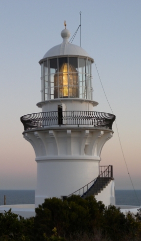 Photograph showing large lantern house with illuminated prismatic lens sitting inside.